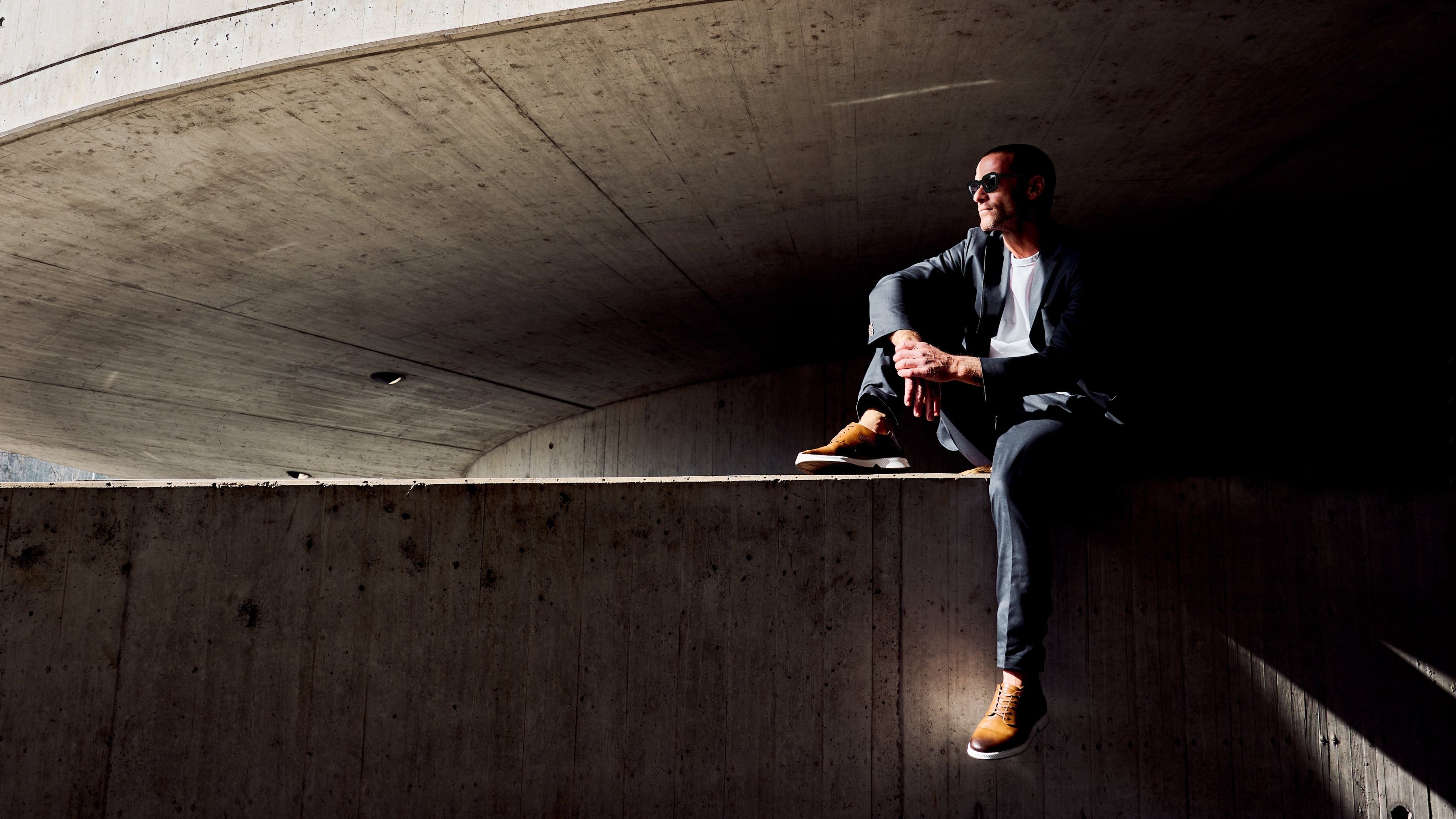 Model wearing RONIN in tan, seated. KANREY derby shoes in tan.